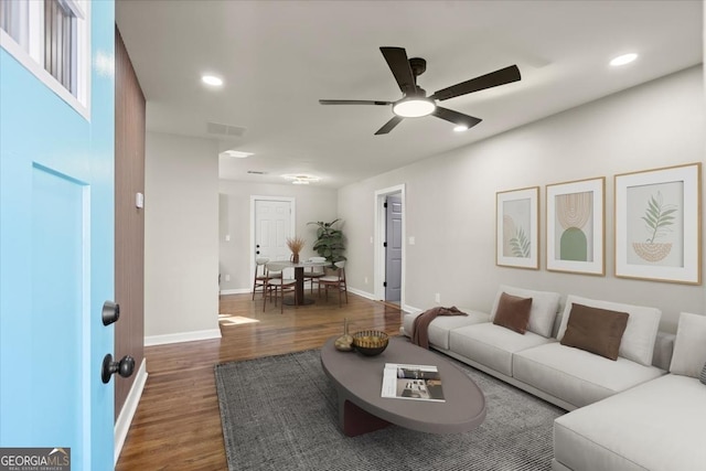 living room with dark hardwood / wood-style flooring and ceiling fan