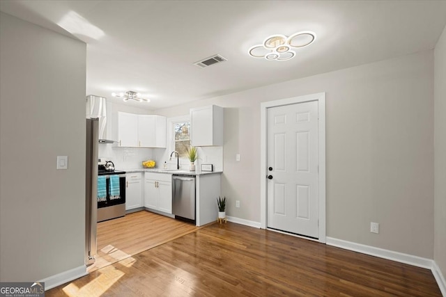 kitchen with sink, tasteful backsplash, light hardwood / wood-style flooring, stainless steel appliances, and white cabinets