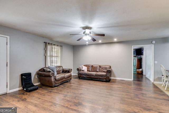 living room with ceiling fan, dark hardwood / wood-style flooring, and a textured ceiling