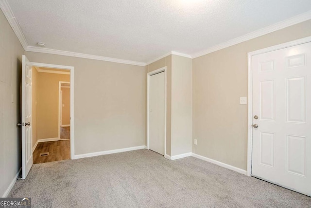 carpeted empty room featuring ornamental molding and a textured ceiling