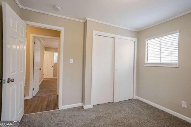 unfurnished bedroom with crown molding, a closet, and carpet