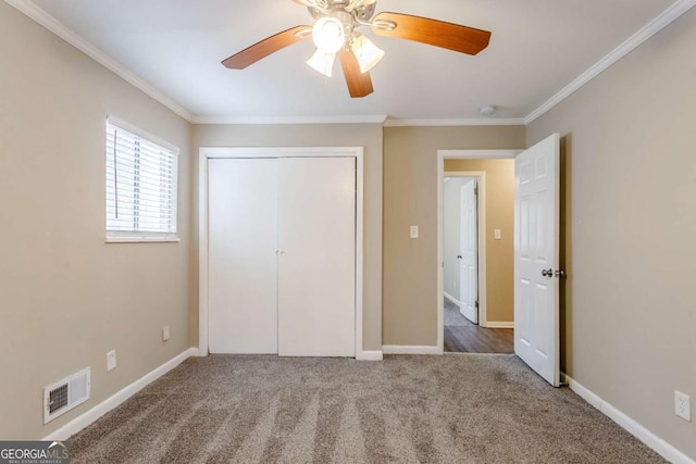 unfurnished bedroom with ornamental molding, a closet, ceiling fan, and carpet