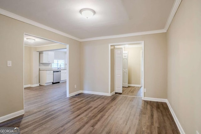 spare room with wood-type flooring, ornamental molding, and sink