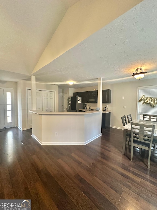 kitchen with stainless steel refrigerator, dark hardwood / wood-style flooring, vaulted ceiling, and a kitchen island