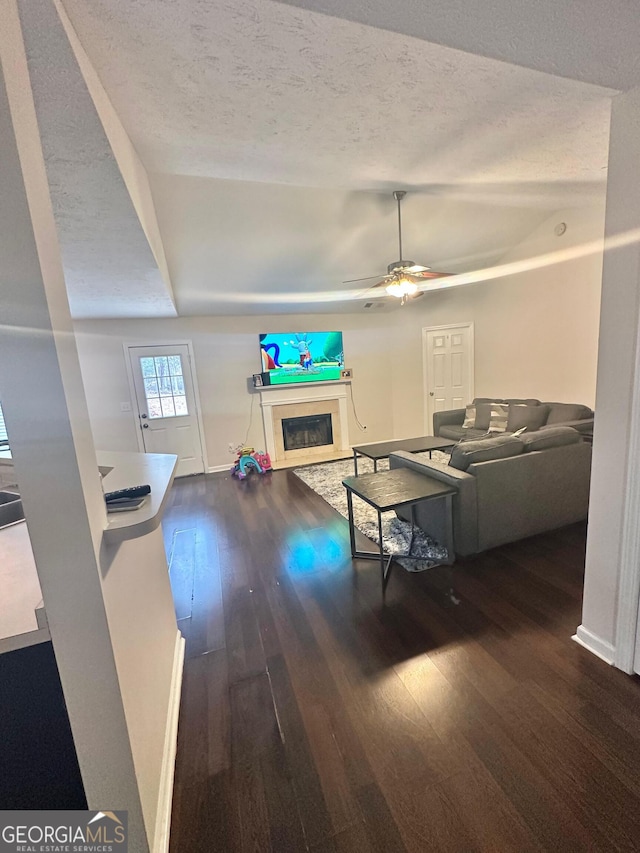 living room featuring ceiling fan, dark hardwood / wood-style flooring, and a textured ceiling