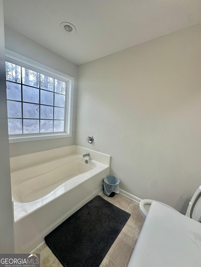 bathroom featuring tile patterned floors, toilet, and a bathing tub