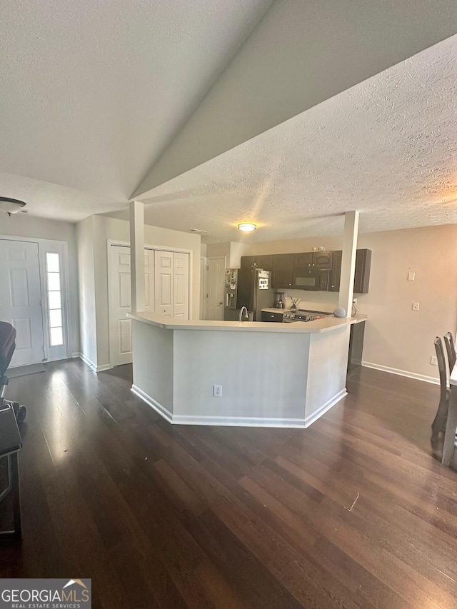 kitchen with stainless steel fridge with ice dispenser, vaulted ceiling, dark hardwood / wood-style floors, and a textured ceiling