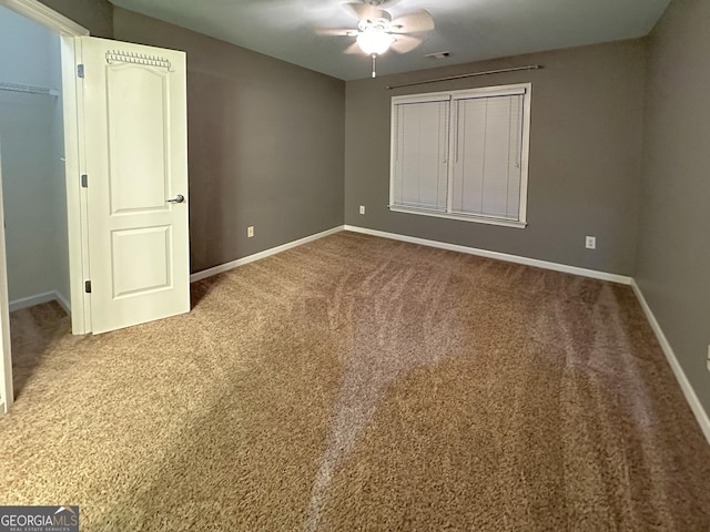 unfurnished bedroom with ceiling fan, carpet floors, a closet, and a walk in closet