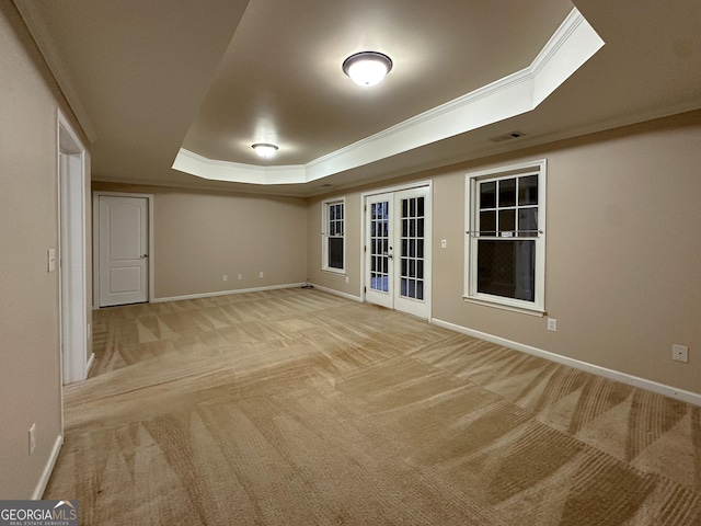 interior space featuring crown molding, a tray ceiling, light colored carpet, and french doors