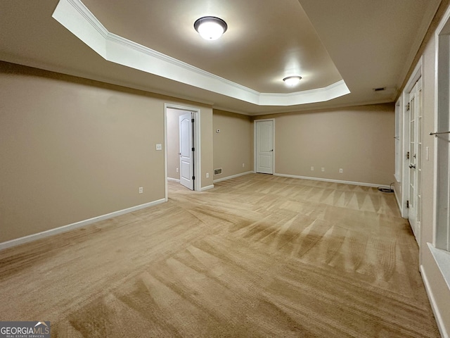 unfurnished bedroom featuring a raised ceiling, ornamental molding, and light colored carpet