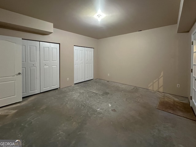 unfurnished bedroom featuring two closets and concrete floors