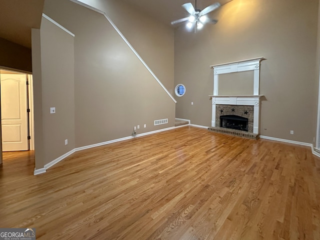 unfurnished living room featuring a brick fireplace, ceiling fan, and light hardwood / wood-style flooring