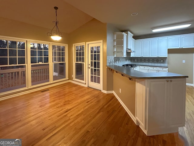 kitchen with white cabinetry, backsplash, decorative light fixtures, vaulted ceiling, and kitchen peninsula