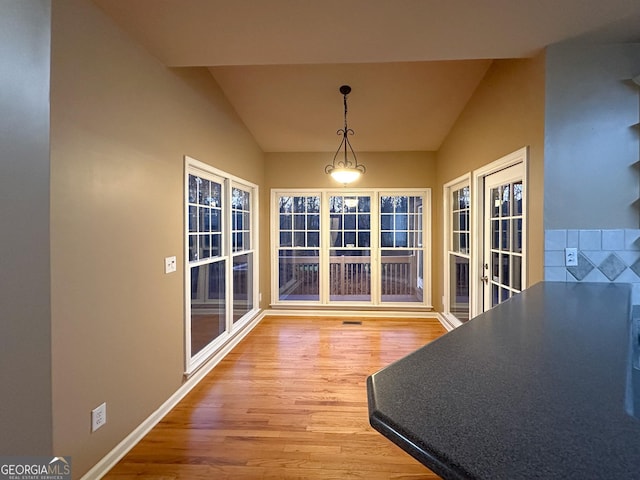 unfurnished dining area featuring vaulted ceiling and hardwood / wood-style floors