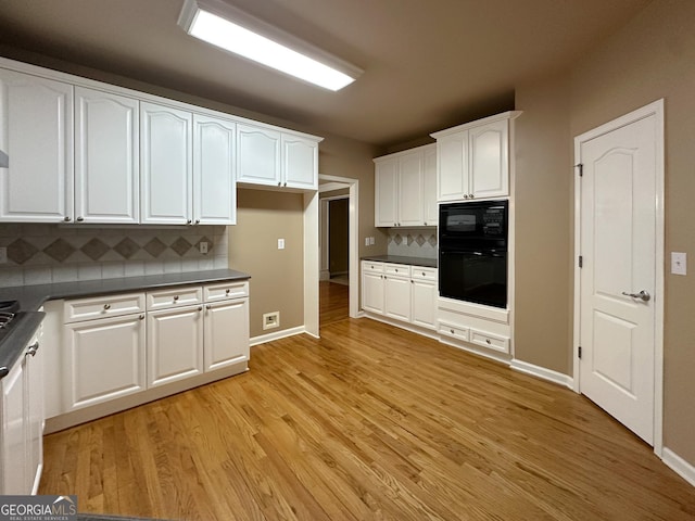 kitchen featuring black appliances, white cabinets, light hardwood / wood-style floors, and decorative backsplash