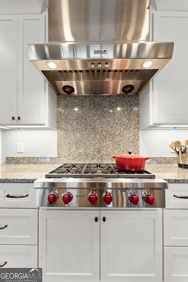 kitchen with wall chimney range hood, white cabinetry, light stone counters, tasteful backsplash, and stainless steel gas cooktop