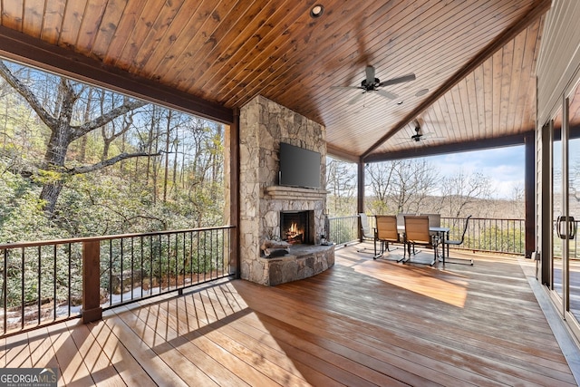 wooden terrace with ceiling fan and an outdoor stone fireplace