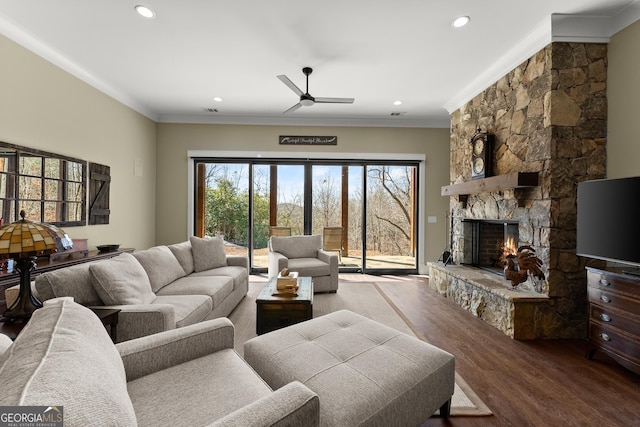 living room with hardwood / wood-style floors, a fireplace, ornamental molding, and ceiling fan