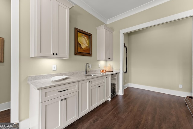 kitchen with sink, white cabinetry, wine cooler, ornamental molding, and light stone countertops