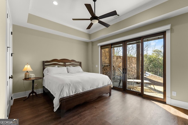 bedroom with a raised ceiling, dark hardwood / wood-style flooring, access to exterior, and ceiling fan