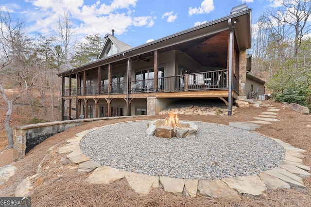 rear view of house featuring ceiling fan, a balcony, and a fire pit