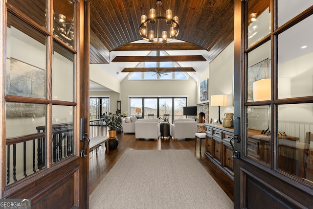 interior space with a stone fireplace, dark hardwood / wood-style floors, high vaulted ceiling, wooden ceiling, and an inviting chandelier