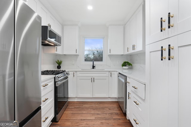 kitchen with sink, backsplash, appliances with stainless steel finishes, and white cabinets