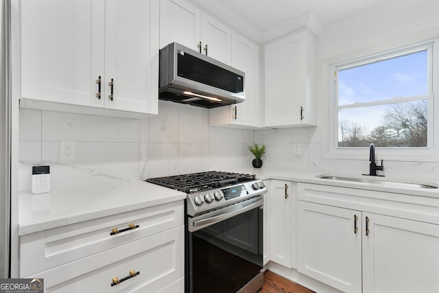 kitchen with sink, stainless steel appliances, white cabinetry, and light stone counters