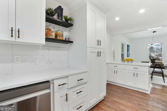 kitchen featuring hanging light fixtures, wood-type flooring, light stone countertops, stainless steel dishwasher, and white cabinetry