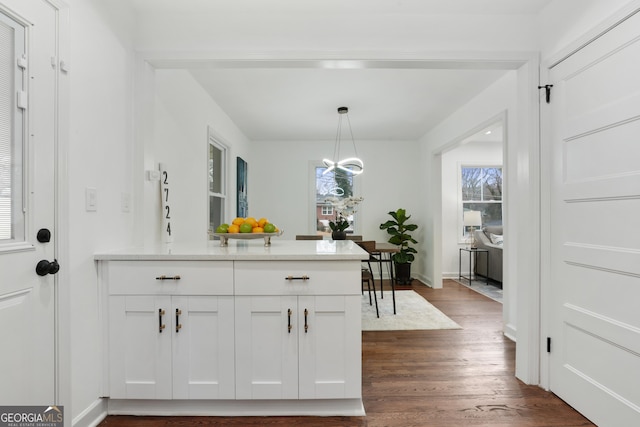 kitchen featuring dark wood-type flooring, white cabinets, hanging light fixtures, and a notable chandelier