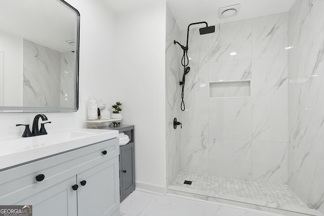 bathroom with tiled shower and vanity