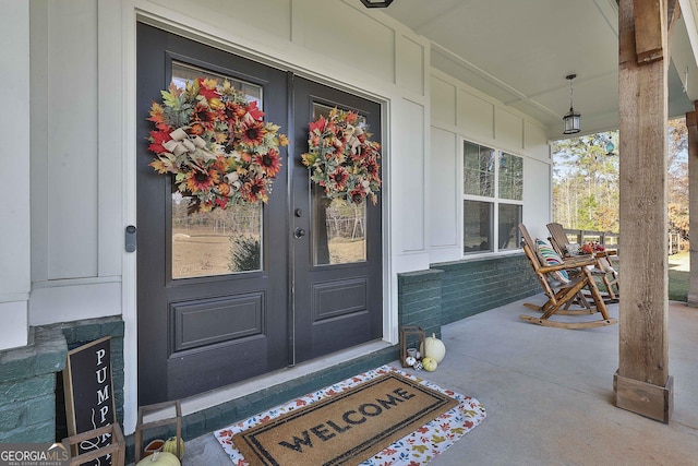 view of exterior entry with a porch and french doors