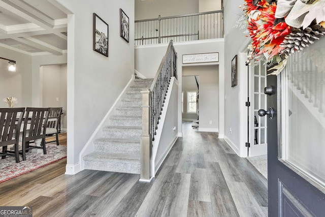 foyer with coffered ceiling, wood-type flooring, ornamental molding, and beamed ceiling