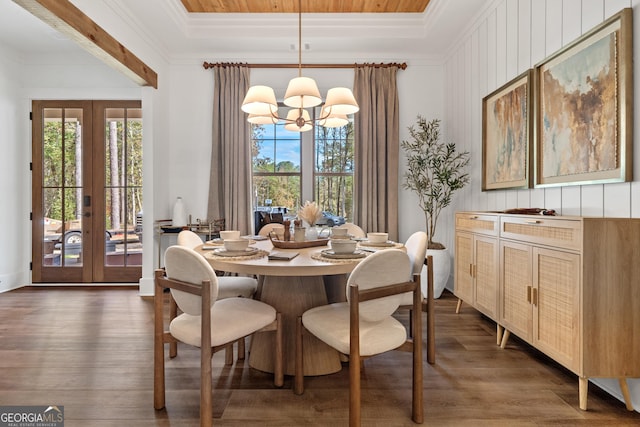 dining space with dark wood-style floors, plenty of natural light, ornamental molding, and an inviting chandelier