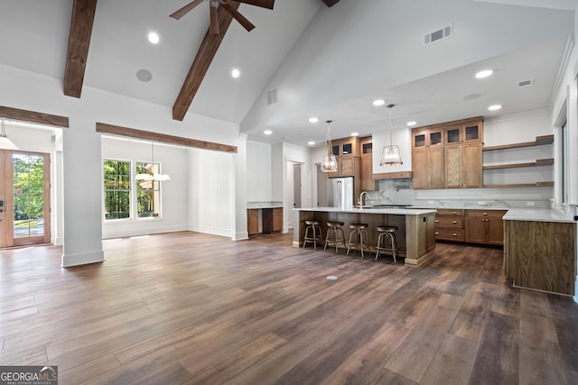 kitchen with visible vents, glass insert cabinets, brown cabinets, a kitchen breakfast bar, and light countertops