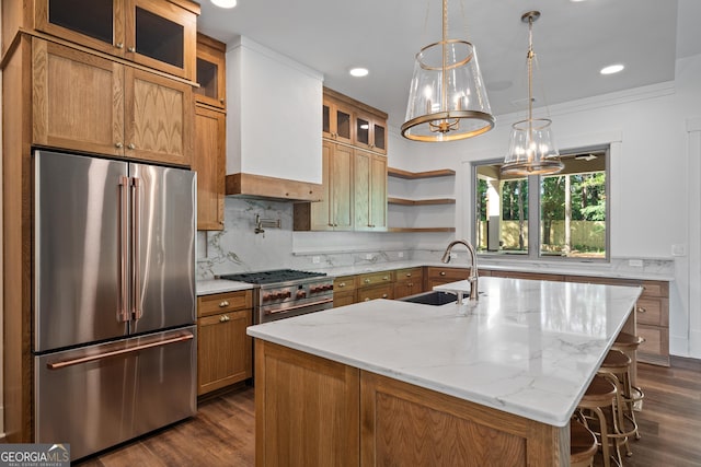 kitchen with a center island with sink, glass insert cabinets, light stone counters, and premium appliances