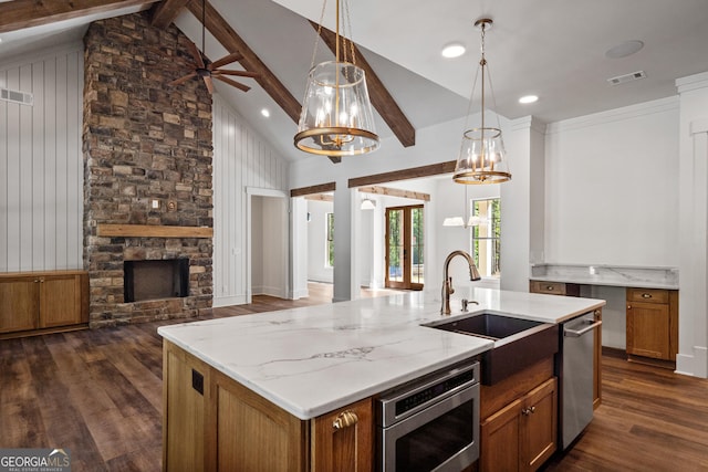 kitchen featuring visible vents, an island with sink, appliances with stainless steel finishes, brown cabinets, and open floor plan