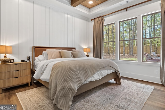 bedroom featuring wood finished floors, beam ceiling, visible vents, and multiple windows