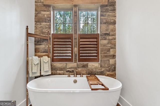 full bath with baseboards and a freestanding bath