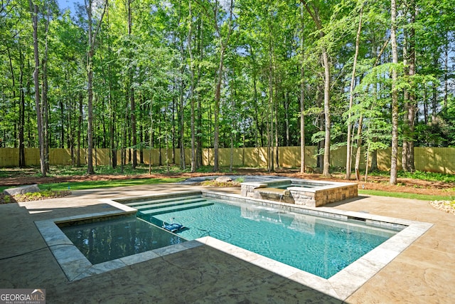 view of swimming pool with a fenced backyard, a pool with connected hot tub, and a patio