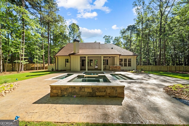 back of property with a fenced in pool, a fenced backyard, board and batten siding, and an in ground hot tub