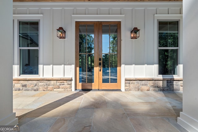 entrance to property featuring stone siding, board and batten siding, and french doors