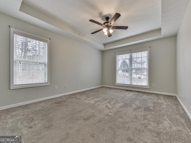 empty room featuring carpet flooring, ceiling fan, and a tray ceiling