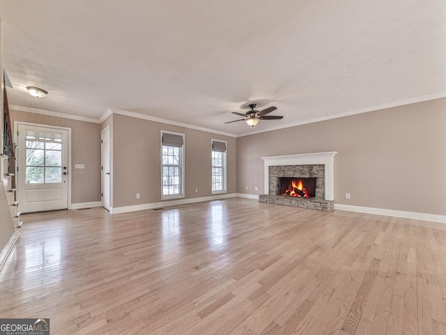 unfurnished living room featuring crown molding, a stone fireplace, and a wealth of natural light