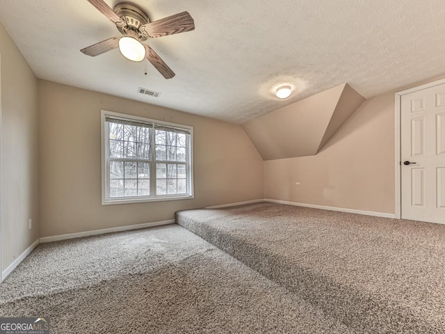 additional living space featuring lofted ceiling, ceiling fan, carpet floors, and a textured ceiling