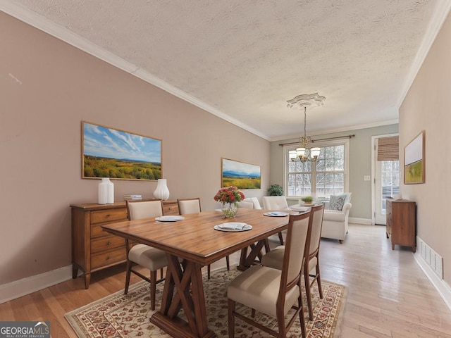 dining room featuring ornamental molding, a chandelier, a textured ceiling, and light hardwood / wood-style flooring