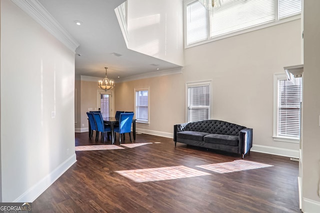 living area with a notable chandelier, crown molding, dark hardwood / wood-style floors, and a towering ceiling