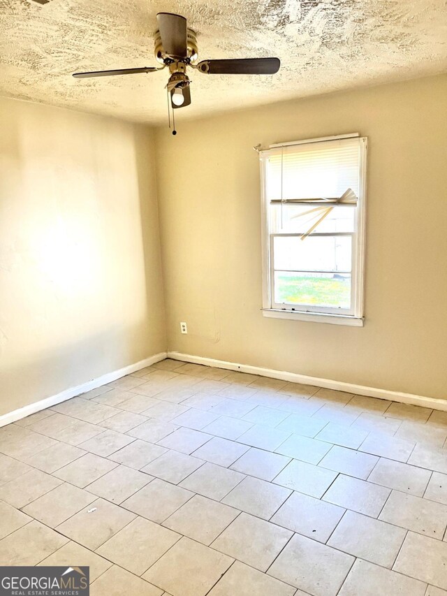 spare room featuring light tile patterned floors, a textured ceiling, and ceiling fan