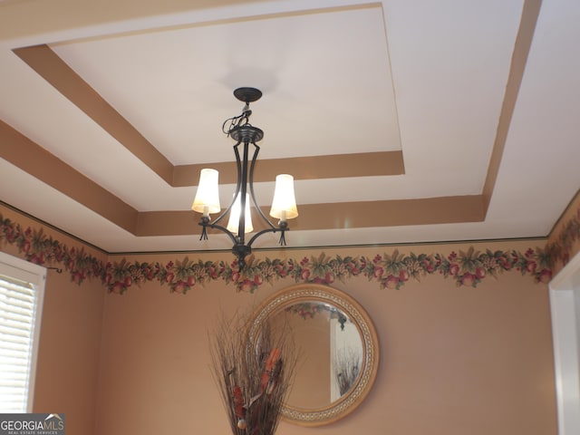 details featuring a raised ceiling and a chandelier