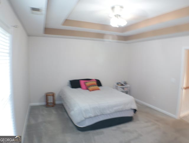 bedroom featuring a raised ceiling and carpet